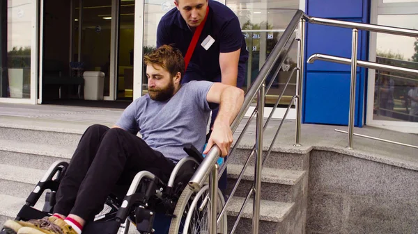 Muž pomáhá přesunout dolů postižený člověk — Stock fotografie