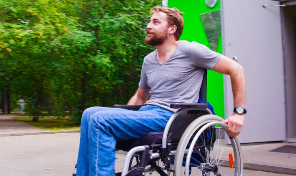 Joven hombre incapacitado caminando en el parque en silla de ruedas —  Fotos de Stock