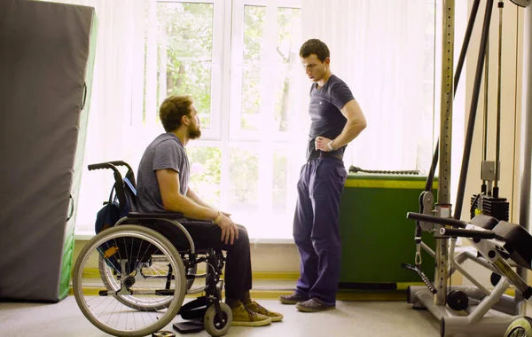 Людина з обмеженими можливостями в інвалідному візку розмовляє з лікарем — стокове фото