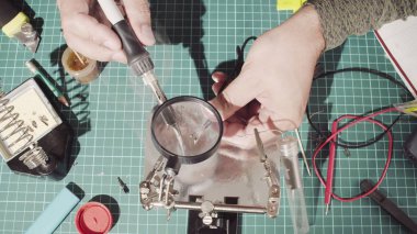 Elektronik cihazlar için bir tel onarılıyor. Erkek lehim teli eller