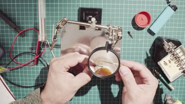 Elektronik cihazlar için bir tel onarılıyor. Erkek lehim teli eller