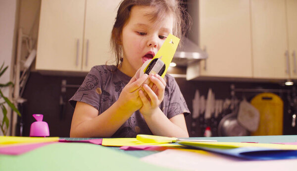 Little girl cutting birds from yellow paper