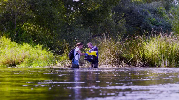 Dva vědci ekologové v vysoké gumové boty stát ve vodě Lesní řeky — Stock fotografie