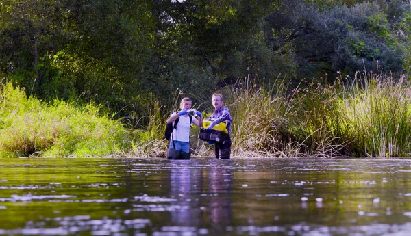 Twee wetenschappers ecologen in hoge rubber laarzen staande in het water van de rivier de bos — Stockfoto
