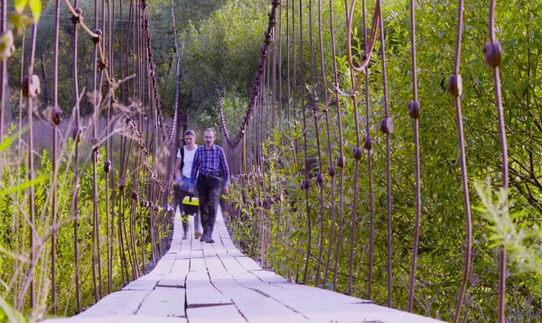 Два ученых-эколога в высоких резиновых сапогах ходят по висячему мосту — стоковое фото