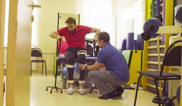 Dokter fysiotherapeut zetten de orthese van gehandicapte man — Stockfoto