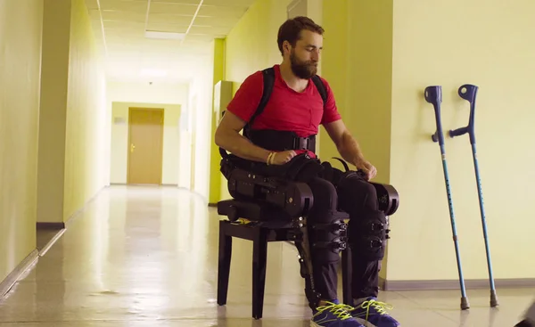 Вимкнути людину в роботизованому екзоскелеті, що сидить на лавці — стокове фото