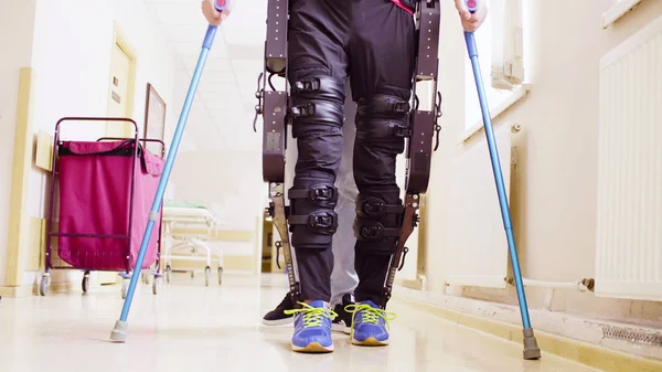 Beine von Behinderten in Roboter-Exoskelett durch den Korridor laufen — Stockfoto