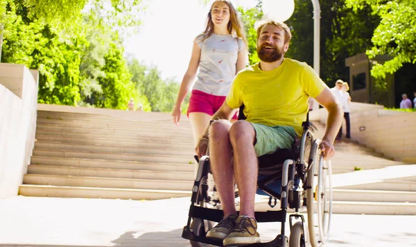 Mladá zakázat člověka na vozíku, procházky v parku se svou ženou — Stock fotografie