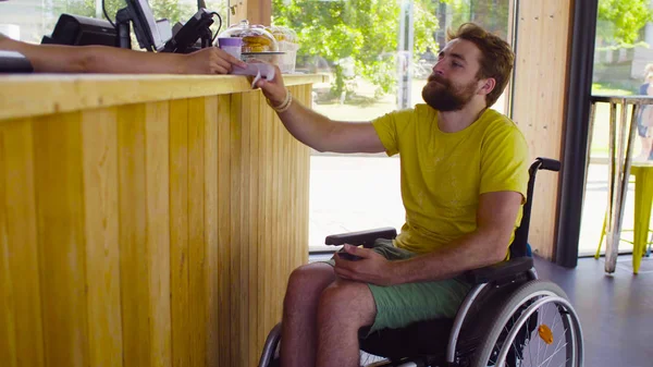 Joven hombre incapacitado en silla de ruedas en el café —  Fotos de Stock