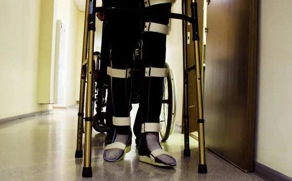 Benen van gehandicapte man in orthese wandelen met een wandelende frame — Stockfoto