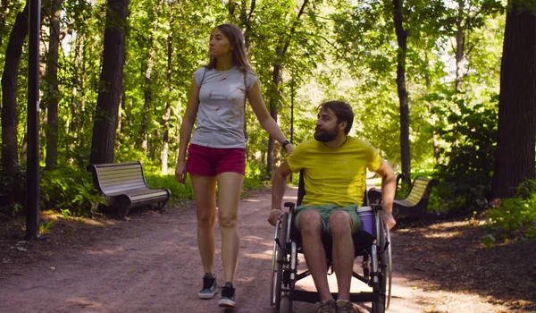 若い妻と公園を歩いて車椅子の人を無効にします。 ロイヤリティフリーのストック写真