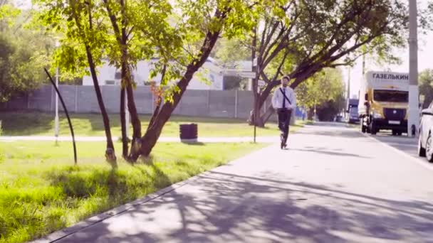 Un hombre con un traje de negocios montando un patinete scooter — Vídeos de Stock