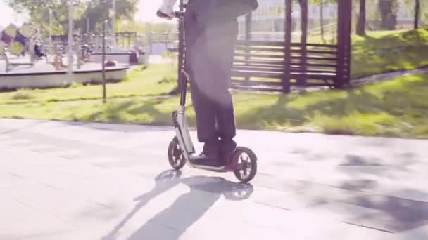 Un hombre con un traje de negocios montando un patinete scooter — Vídeos de Stock