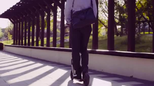 Un hombre con un traje de negocios montando un patinete scooter — Vídeos de Stock