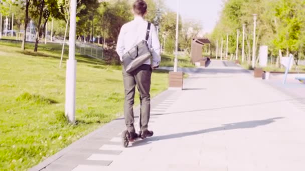 Un hombre con un traje de negocios montando un patinete scooter — Vídeos de Stock