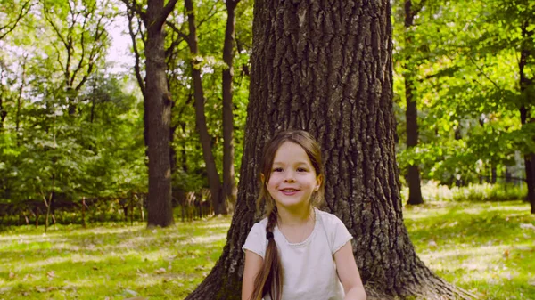 Egy lány ül a parkban, a füvön, közel a fa — Stock Fotó