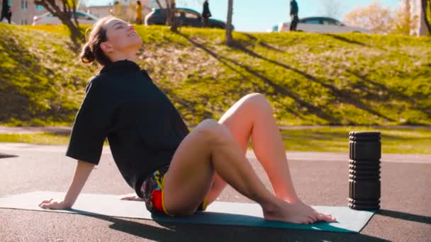 Жінка сидить на килимку і робить розслаблюючі вправи з м'ячем — стокове відео