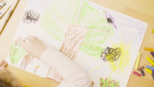 Une fille dessine des crayons pastel sur papier à une table dans une pièce — Video