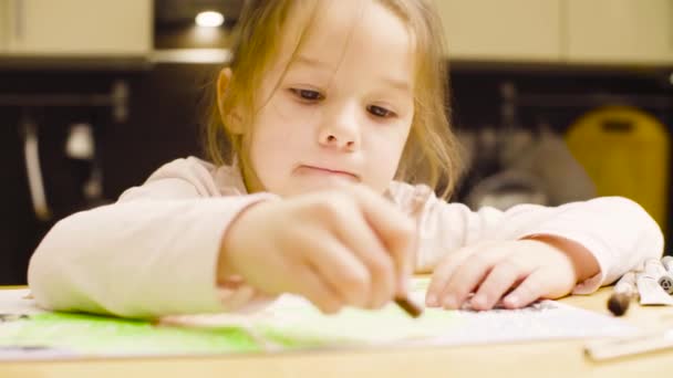 Een meisje pastel krijtjes puttend uit papier op een tafel — Stockvideo