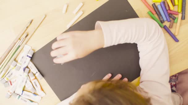 Young artist drawing on black paper with pastel crayons — Stock Video