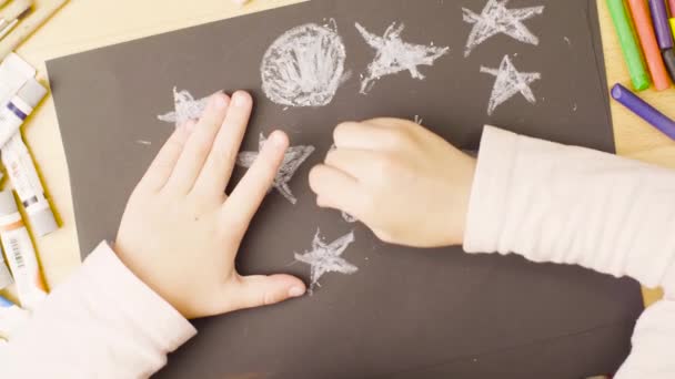Een meisje pastel krijtjes puttend uit papier op een tafel in een kamer — Stockvideo
