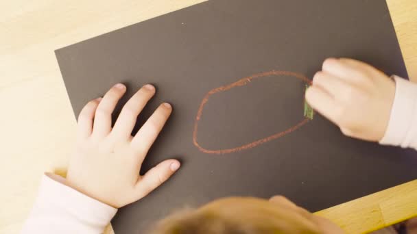 La muchacha que dibuja los lápices de colores pastel sobre el papel a la mesa en la habitación — Vídeos de Stock