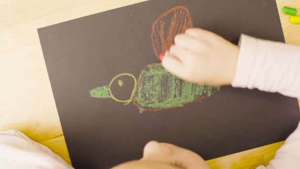 Een meisje pastel krijtjes puttend uit papier op een tafel in een kamer — Stockvideo