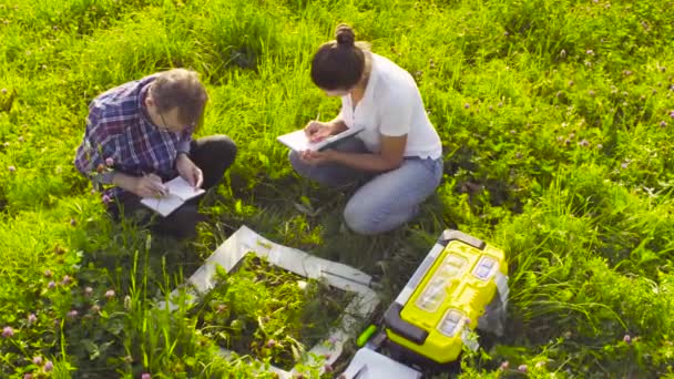 Dois ecologistas examinando plantas no prado — Vídeo de Stock