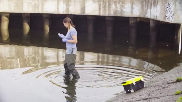Женщина-эколог измеряет pH воды в реке города . — стоковое видео