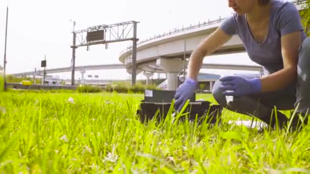 Woman ecologist getting samples of soil near highway. — Stock Video