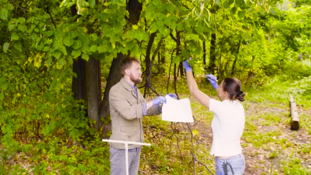 Двоє екологів отримують зразки листя в міському парку — стокове відео