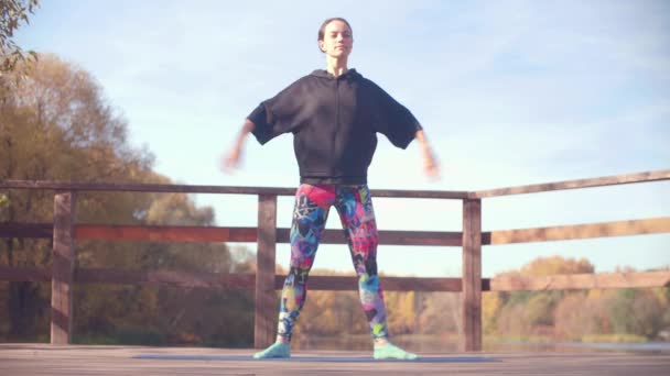 Женщина, делающая хореографические упражнения на мосту в парке — стоковое видео
