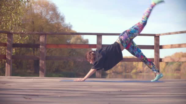 Vrouw doen choreografische oefeningen op de brug in het park — Stockvideo