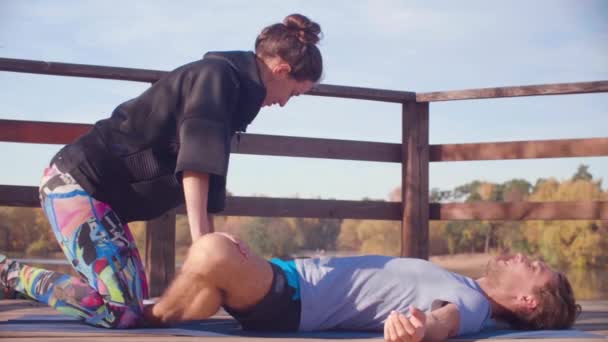 Kvinnan gör stretching övningar för en man — Stockvideo