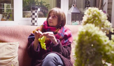 Sıcak giysiler kanepede oturan orta yaşlı kadın