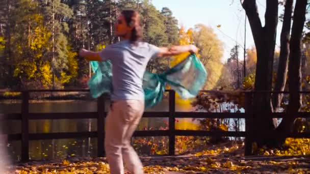 Ein Mann mit einer Stola in den Händen tanzt allein auf der Brücke — Stockvideo