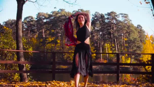 Een vrouw met een rode sjaal in haar handen op de brug alleen dansen — Stockvideo