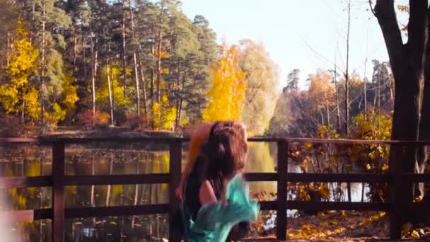 Una donna con una stola blu tra le mani che balla sul ponte da sola — Video Stock