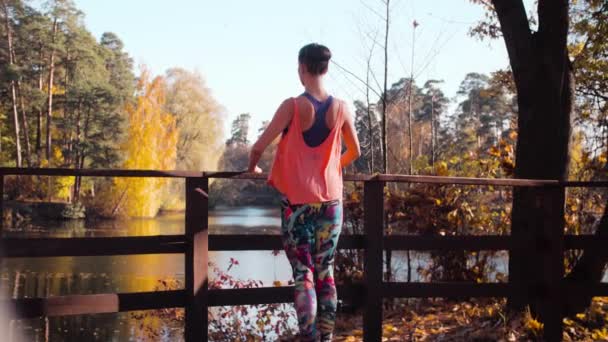 Vrouw doen choreografische oefeningen op de brug in het park — Stockvideo