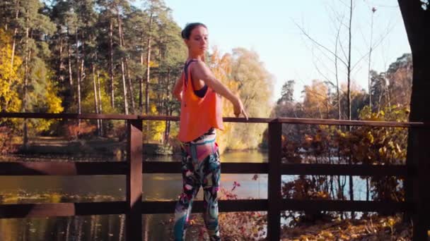 Mujer haciendo ejercicios coreográficos en el puente en el parque — Vídeos de Stock