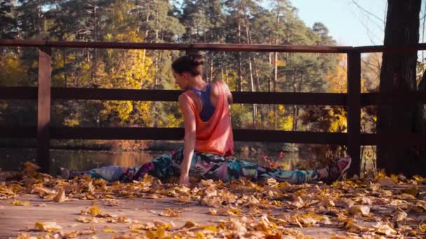 Woman doing choreographic exercises on the bridge in the park — Stock Video