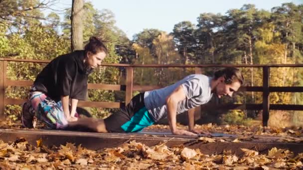 Vrouw doet stretching oefeningen voor een man — Stockvideo