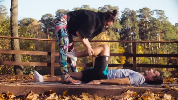 Женщина делает упражнения на растяжку для мужчины — стоковое видео