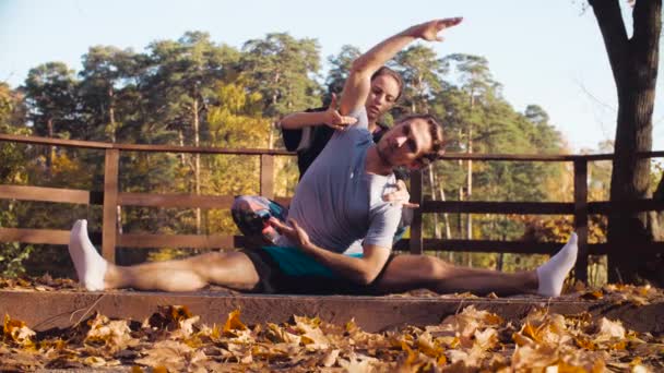 Kvinnan gör stretching övningar för en man — Stockvideo