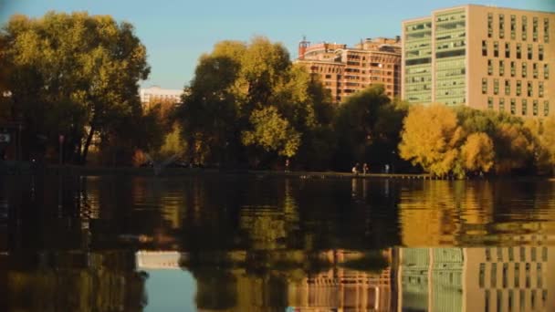 Lago en la ciudad en otoño, árboles reflejados en el agua — Vídeos de Stock