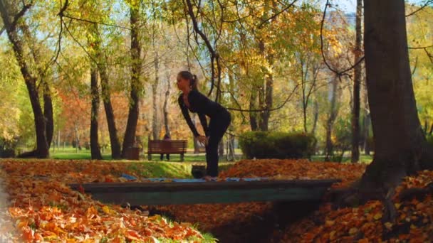 Ung attraktiv kvinna gör yoga exersices i parken — Stockvideo