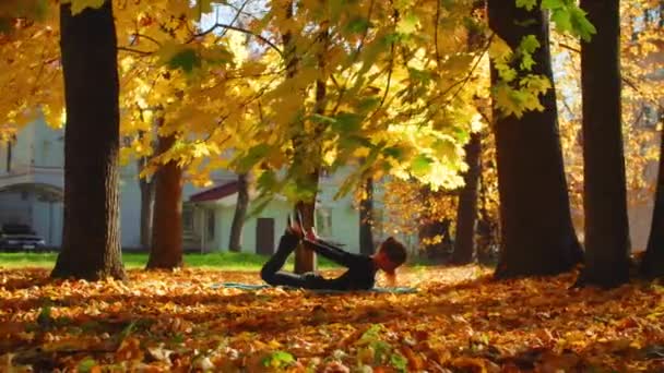 潘枪年轻迷人的女子在公园的弓形姿势做瑜伽 — 图库视频影像