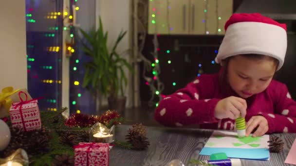 Little girl glues New Year card — Stock Video