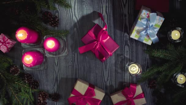 Weihnachtsgeschenke und brennende Kerzen in einem dunklen Raum — Stockvideo